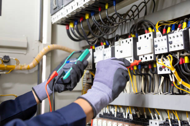 Electrician engineer tests electrical installations and wires on relay protection system. Adjustment of scheme of automation and control of electrical equipment.